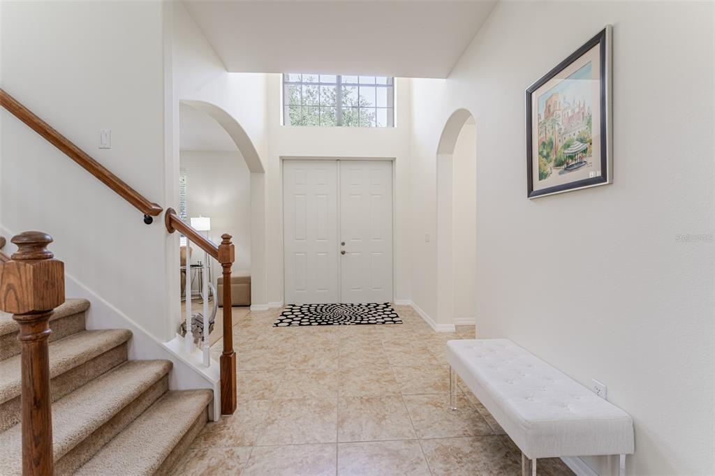 An entryway features a tiled floor, a staircase with a wooden railing, and double doors — 1778 WATERSIDE OAKS DRIVE, ORANGE CITY, FL