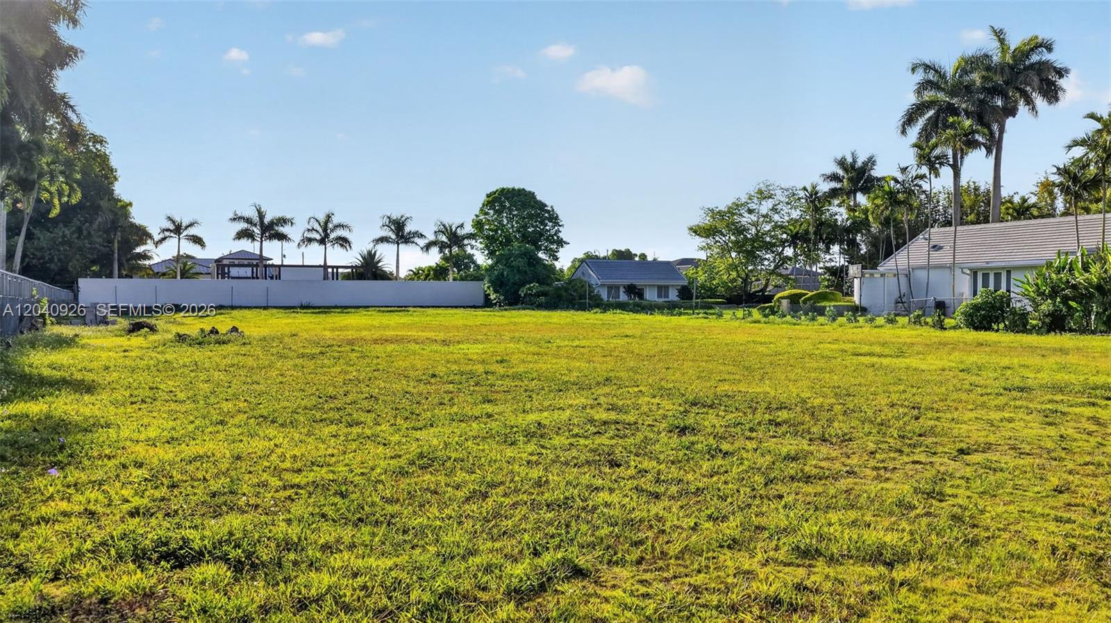 A large, flat, grassy vacant lot is surrounded by palm trees and nearby residential houses — 365 NW 128th AVE, Sweetwater FL 33182, SWEETWATER, FL