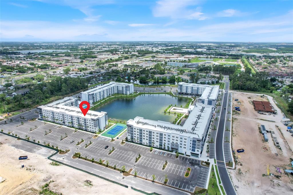 An aerial view shows a large apartment complex surrounding a central pond with parking lots — 5579 MILLENIA PARK BOULEVARD UNIT 508, ORLANDO, FL