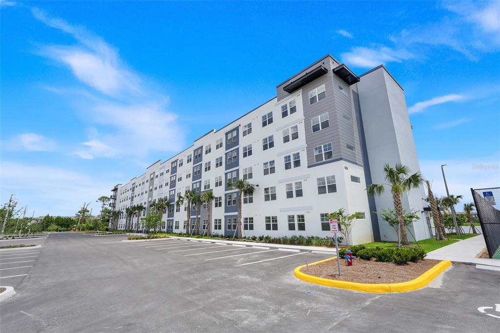 A multi-story apartment building exterior features a paved parking lot and palm trees — 5579 MILLENIA PARK BOULEVARD UNIT 508, ORLANDO, FL