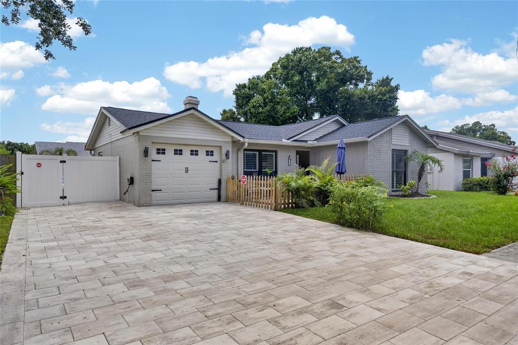 A single-story house with a paved driveway, white garage door, and a small picket fence — 614 STILLVIEW CIRCLE, BRANDON, FL