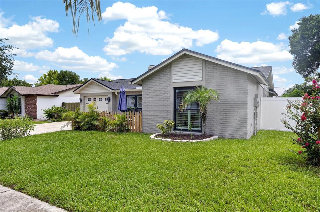 A gray brick house with a front lawn, a small palm tree, and a fence — 614 STILLVIEW CIRCLE, BRANDON, FL