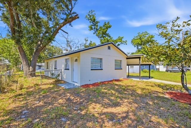 A single-story white house with a carport sits on a grassy lot with trees — 1105 LINCOLN TERRACE, WINTER GARDEN, FL