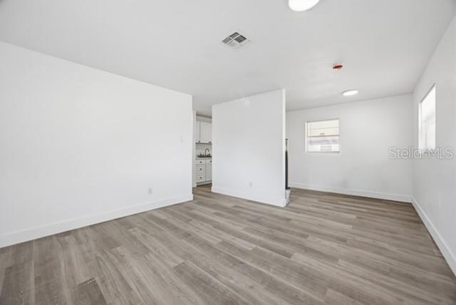 An interior view of a room with white walls, light wood-look flooring, and a partial wall — 1105 LINCOLN TERRACE, WINTER GARDEN, FL