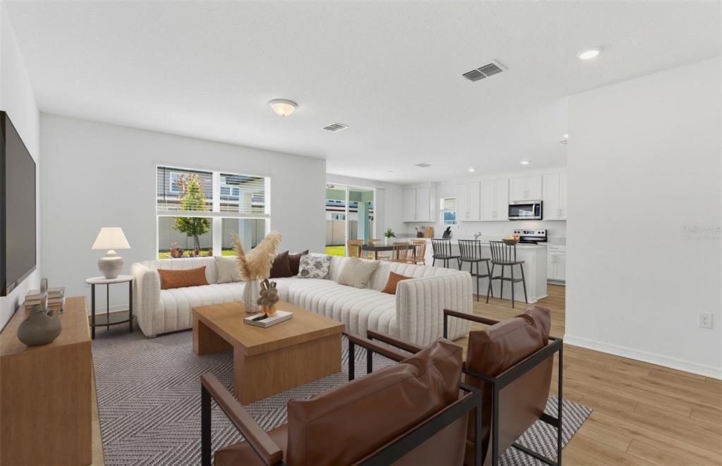 A living room with a sectional sofa and two leather chairs opens to a kitchen — 1090 SILVERLAKE BOULEVARD, LAKE ALFRED, FL