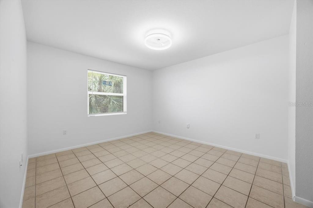 An empty bedroom features white walls, a single window, and light-colored tile flooring — 3028 PARKWAY BOULEVARD UNIT 301, KISSIMMEE, FL