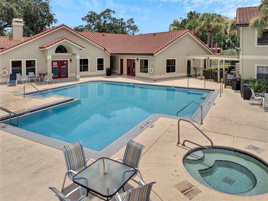 An outdoor swimming pool and hot tub are situated in front of a tan building — 3028 PARKWAY BOULEVARD UNIT 301, KISSIMMEE, FL
