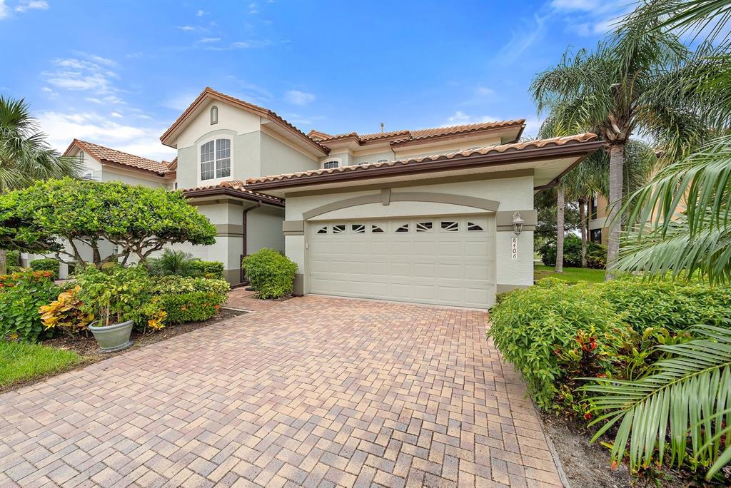 A two-story house with a beige stucco exterior, a tiled roof, and a paved driveway — 8406 MIRAMAR WAY UNIT 8406, LAKEWOOD RANCH, FL