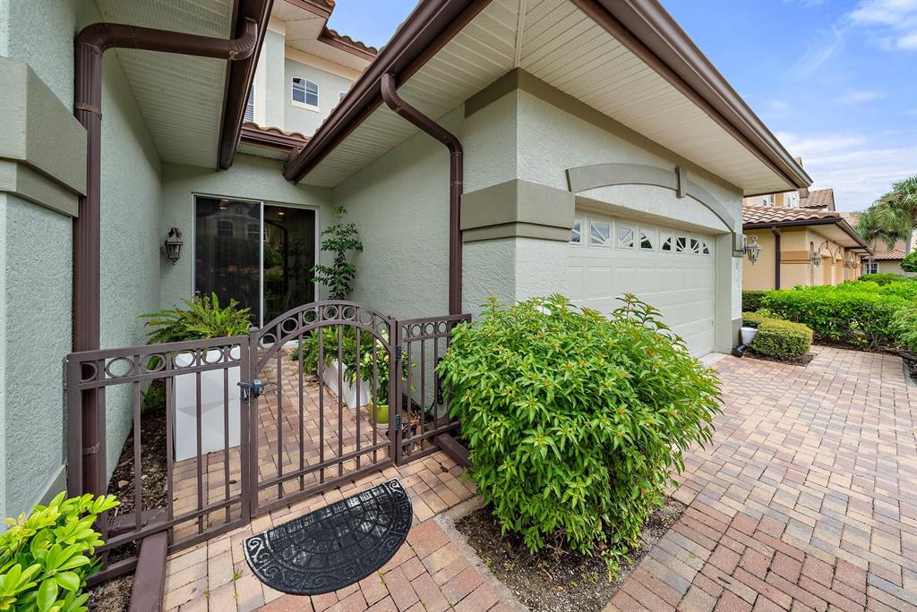 A metal gate leads to a small courtyard entrance with a garage and paved driveway — 8406 MIRAMAR WAY UNIT 8406, LAKEWOOD RANCH, FL