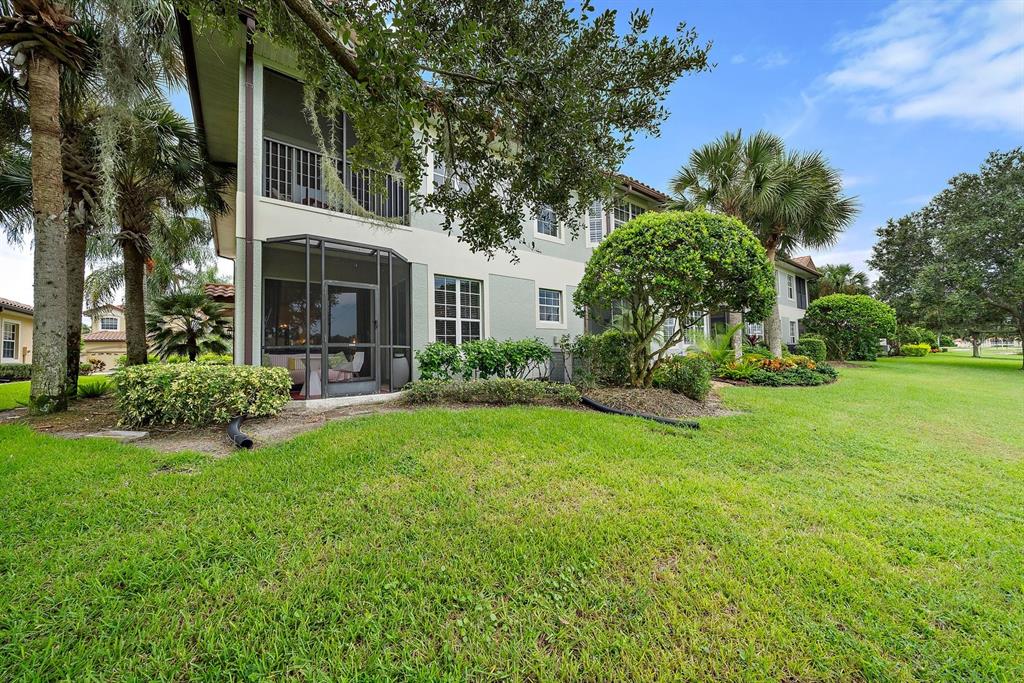 A two-story building with a screened-in porch and balcony sits on a grassy lawn — 8406 MIRAMAR WAY UNIT 8406, LAKEWOOD RANCH, FL