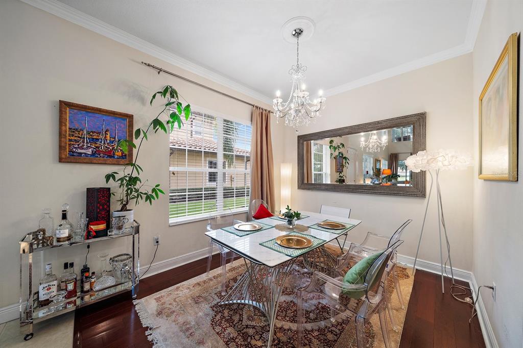 A dining room features a glass table, clear chairs, a large mirror, and a crystal chandelier — 8406 MIRAMAR WAY UNIT 8406, LAKEWOOD RANCH, FL