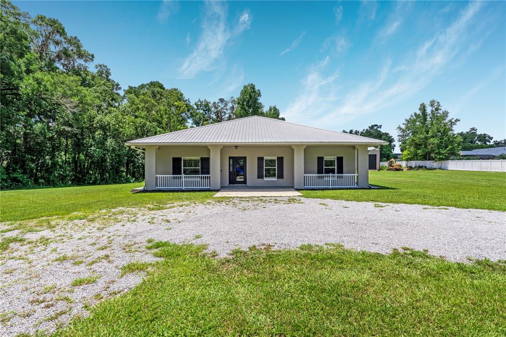 A single-story house with a gravel driveway and a detached garage at sunset — 2287 N SPRING GARDEN AVENUE, DELAND, FL