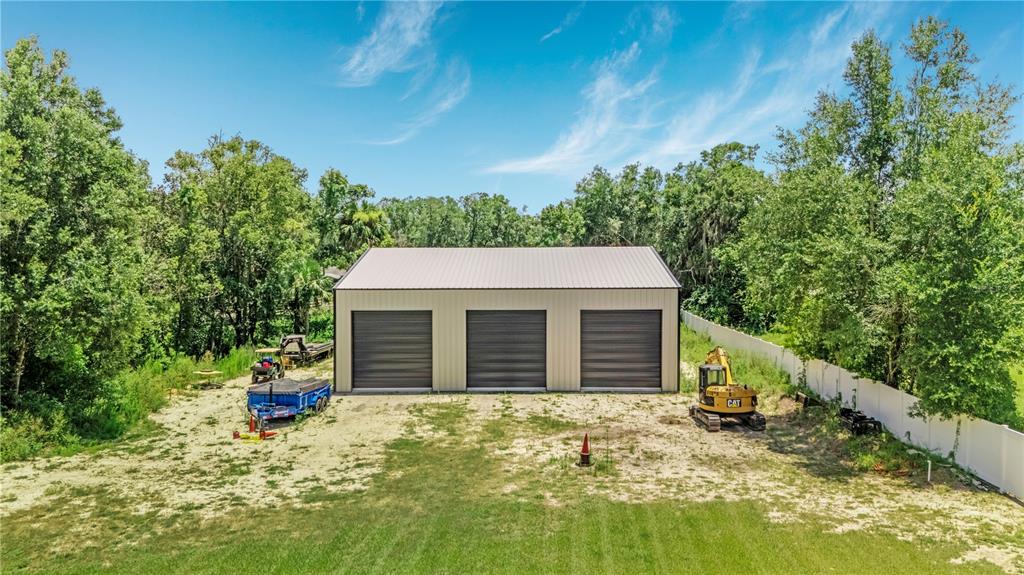 A single-story house with a metal roof and a detached three-car garage on a lawn — 2287 N SPRING GARDEN AVENUE, DELAND, FL