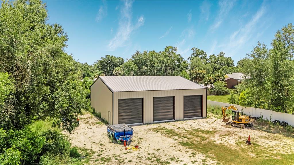 A single-story house with a metal roof and a covered front porch sits on grass — 2287 N SPRING GARDEN AVENUE, DELAND, FL