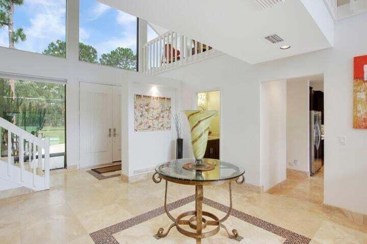 A bright foyer features a glass-topped table, tile flooring, and a staircase leading to a loft — 1328 SE Colony Way, Jupiter FL 33478, JUPITER, FL
