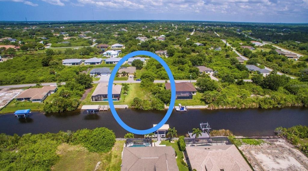An aerial view shows a vacant waterfront lot situated between two existing houses — 9386 BLUEGILL CIRCLE, PORT CHARLOTTE, FL