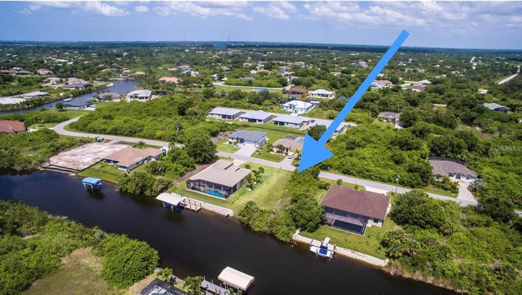 An aerial view shows a vacant waterfront lot situated between two houses along a canal — 9386 BLUEGILL CIRCLE, PORT CHARLOTTE, FL