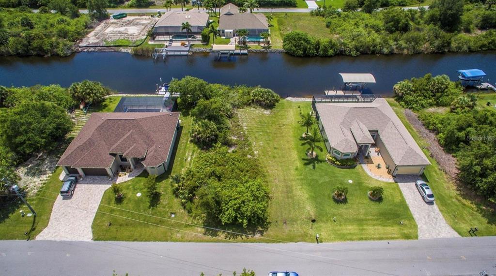 An aerial view shows two houses with pools and boat docks along a canal — 9386 BLUEGILL CIRCLE, PORT CHARLOTTE, FL