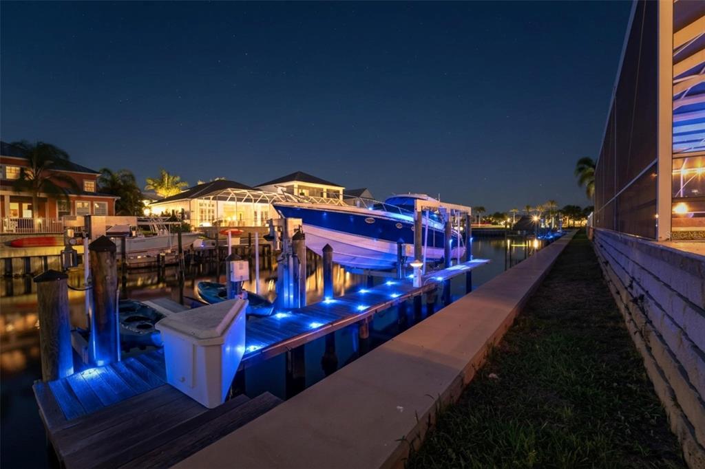 A boat is docked at a private pier with blue deck lighting at night — 613 BALIBAY ROAD, APOLLO BEACH, FL