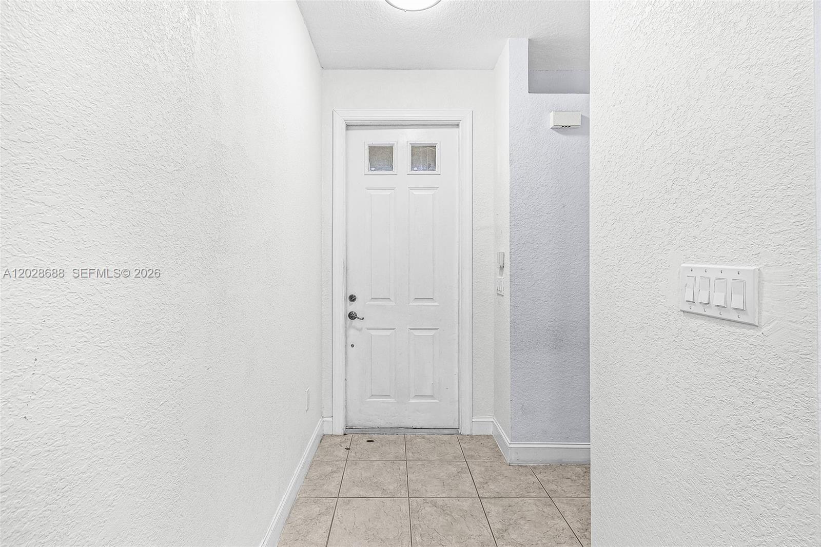 A white door with two glass panels sits at the end of a tiled entryway — 7542 Bristol Cir, Naples FL 34120, NAPLES, FL