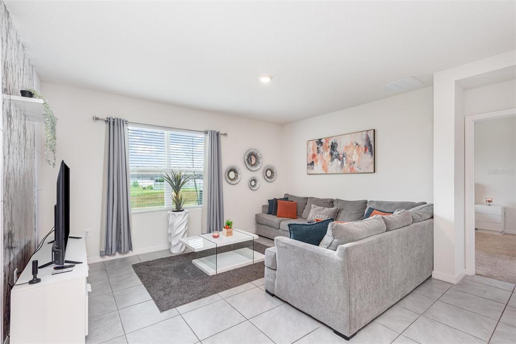 A living room features gray tile flooring, a sectional sofa, and a white coffee table — 1031 AUGUST SKY DRIVE, DELTONA, FL
