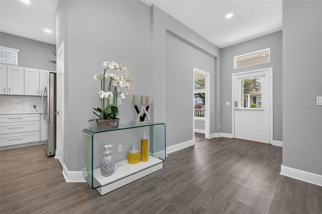 An entryway with gray walls and wood-look flooring features a glass console table and door — 167 LONGVIEW AVENUE, CELEBRATION, FL