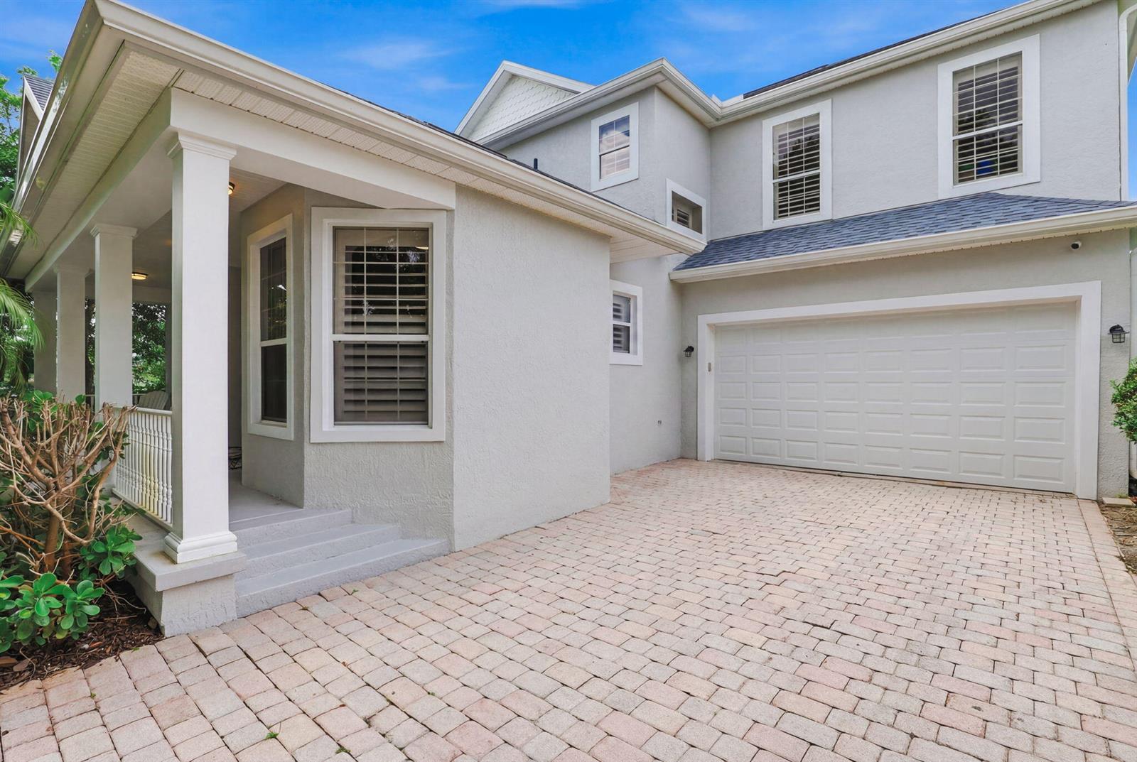 A light gray house exterior features a paved driveway, a garage, and a covered porch — 7501 14th Lane, Vero Beach FL 32966, VERO BEACH, FL
