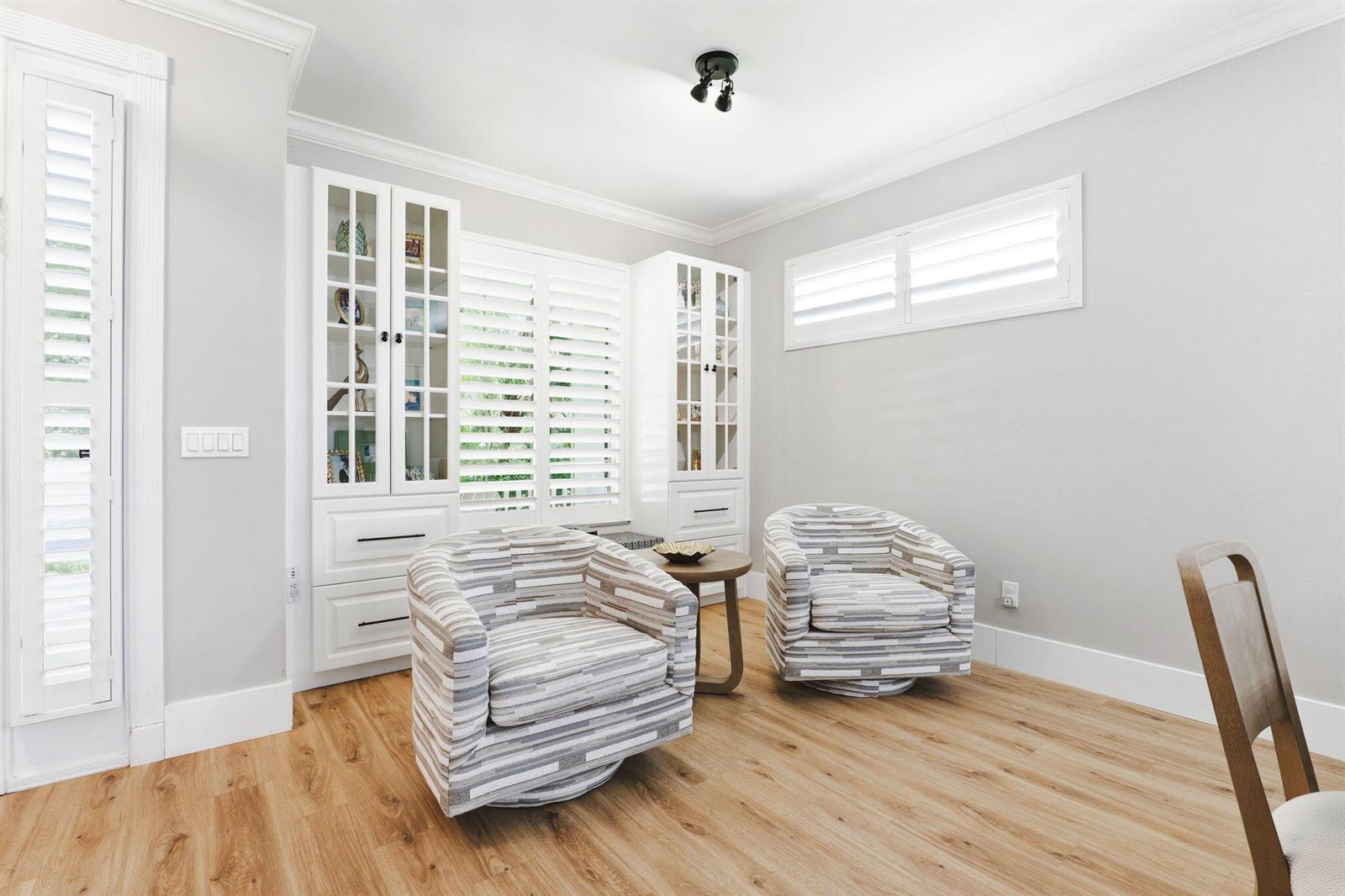 A room with light wood floors, two patterned armchairs, and white built-in display cabinets — 7501 14th Lane, Vero Beach FL 32966, VERO BEACH, FL
