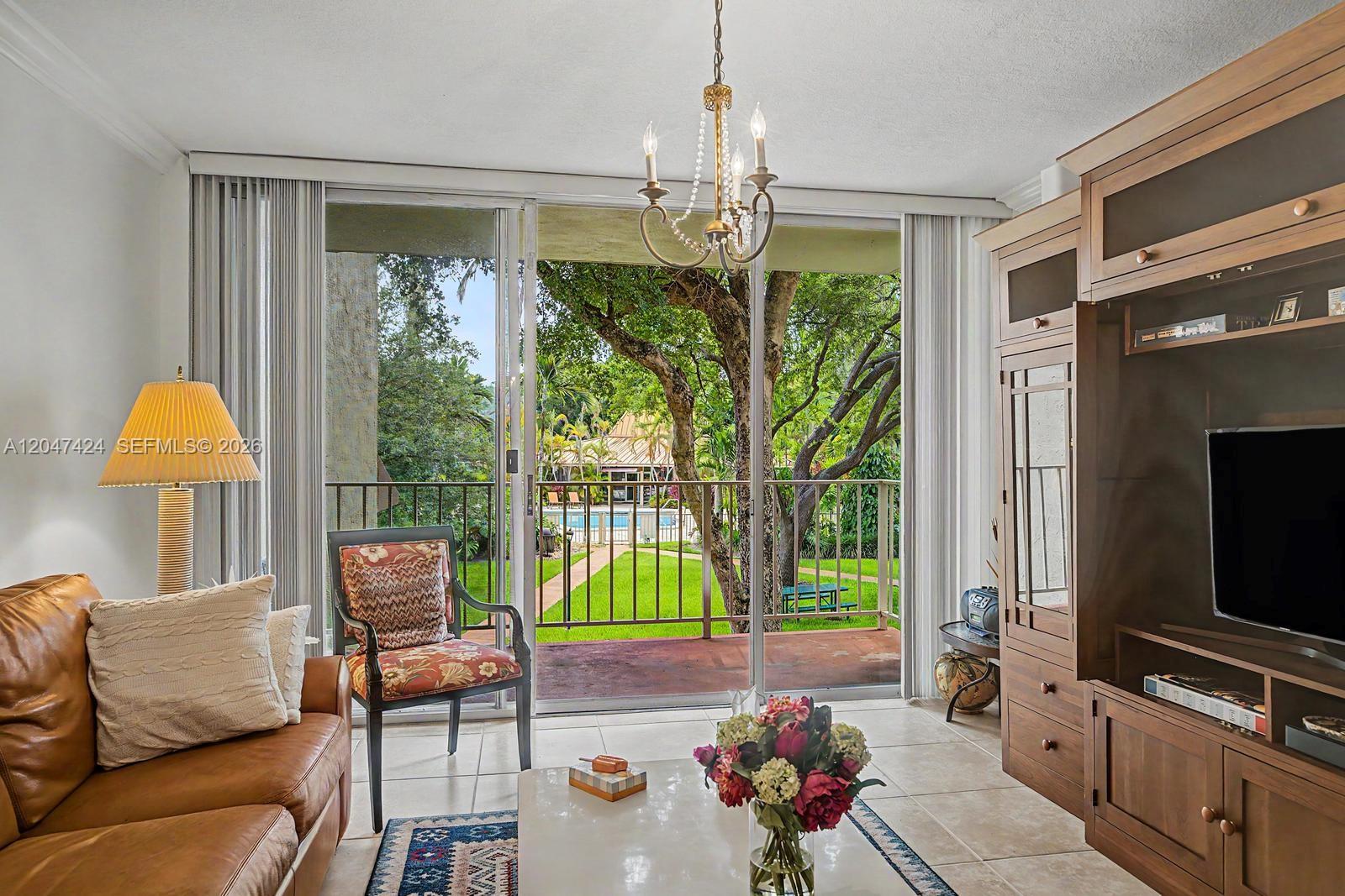 A living room features tile floors, a leather sofa, and sliding glass doors overlooking a pool — 13120 SW 92nd Ave # 207, Miami FL 33176, MIAMI, FL