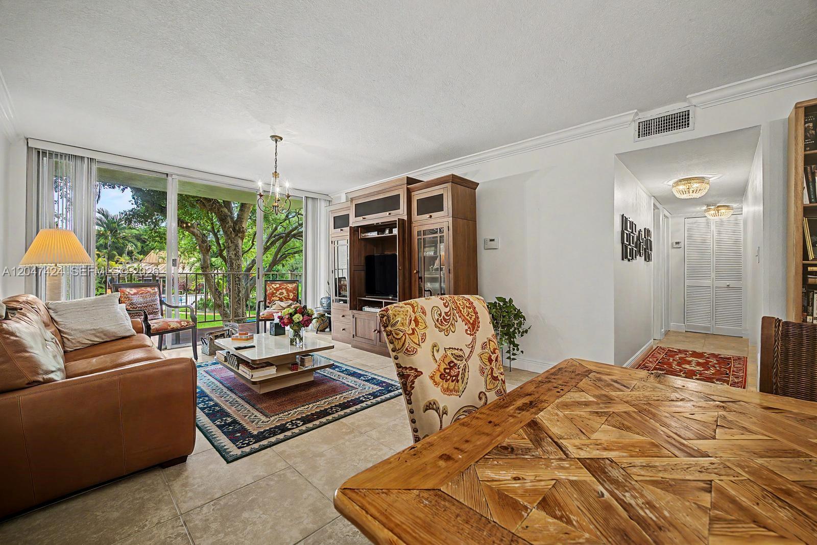 A living room with tile floors, a leather sofa, and a balcony view of trees — 13120 SW 92nd Ave # 207, Miami FL 33176, MIAMI, FL