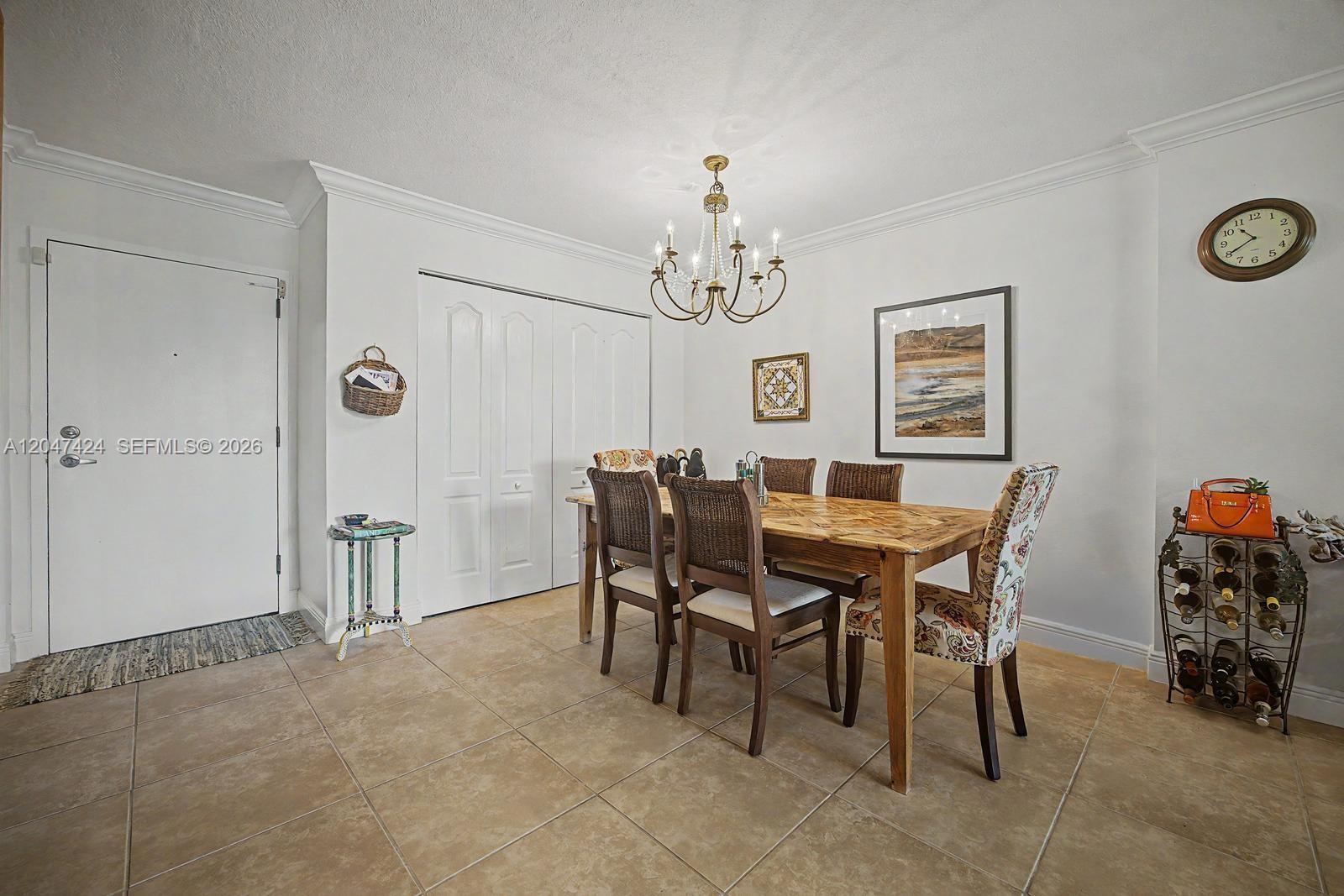 A dining room features a wooden table, wicker chairs, a chandelier, and tile flooring — 13120 SW 92nd Ave # 207, Miami FL 33176, MIAMI, FL