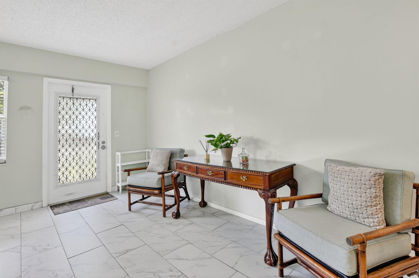 An entryway features light tile flooring, two bamboo-style chairs, and a wooden console table — 415 Mansfield # J, Boca Raton FL 33434, BOCA RATON, FL