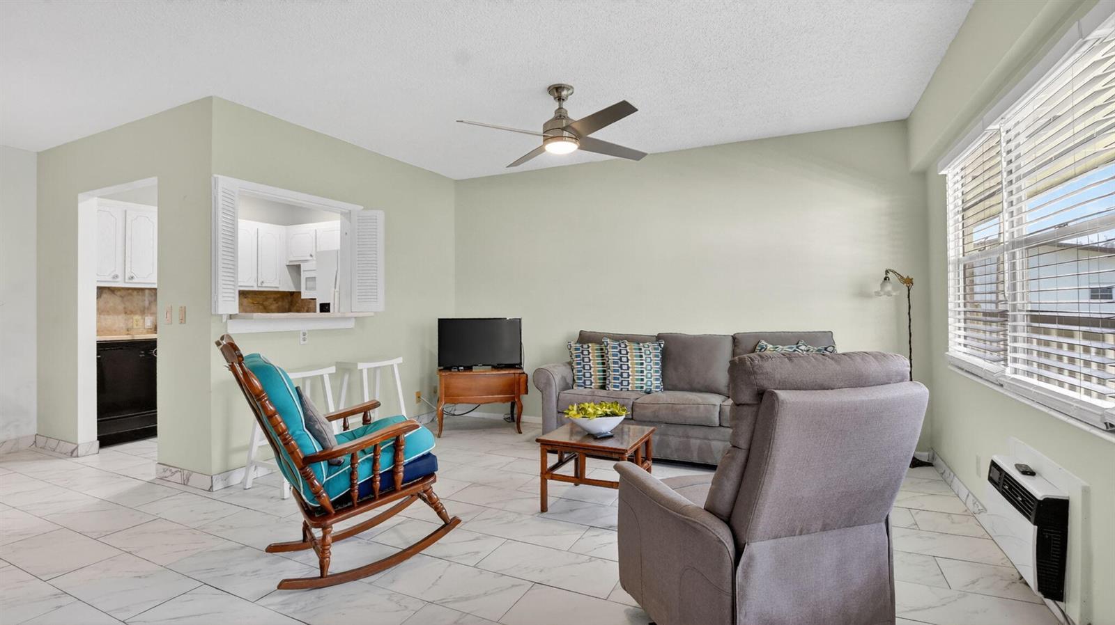 A living room features light green walls, white tile flooring, a ceiling fan, and furniture — 415 Mansfield # J, Boca Raton FL 33434, BOCA RATON, FL
