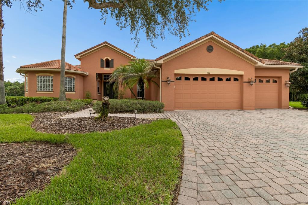 A single-story stucco house with a tile roof, three-car garage, and a paved driveway — 501 MONTAGE LN, POINCIANA, FL