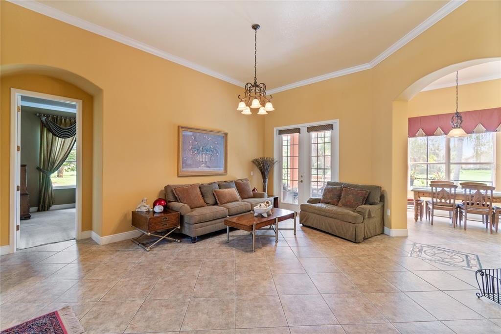 A living room with tile floors, a sofa, a loveseat, and a chandelier — 501 MONTAGE LN, POINCIANA, FL