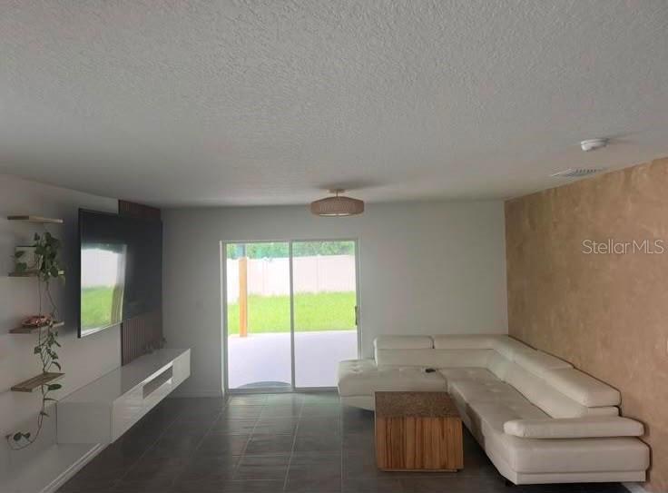 A living room features a white sectional sofa, a wall-mounted console, and a sliding door — 37389 SHARKS EYE LANE, ZEPHYRHILLS, FL