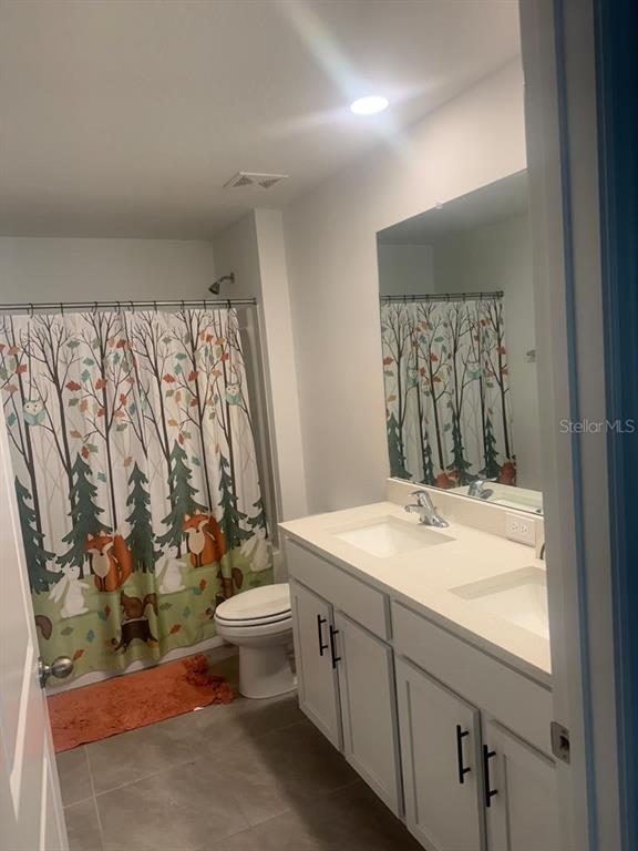 A bathroom features a double vanity with white cabinets, a mirror, and a shower curtain — 37389 SHARKS EYE LANE, ZEPHYRHILLS, FL