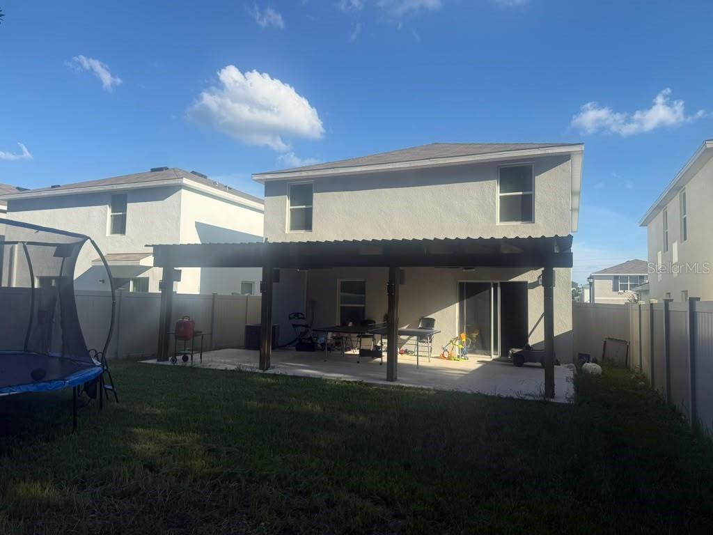 The backyard features a concrete patio covered by a wooden pergola attached to the house — 37389 SHARKS EYE LANE, ZEPHYRHILLS, FL