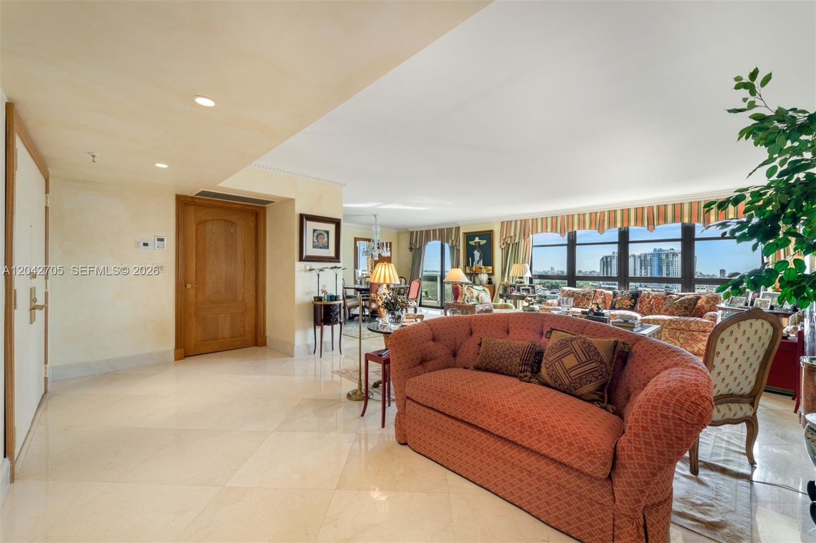 A living room features a tufted red sofa, marble floors, and floor-to-ceiling windows — 9 Island Ave # 1514, Miami Beach FL 33139, MIAMI BEACH, FL