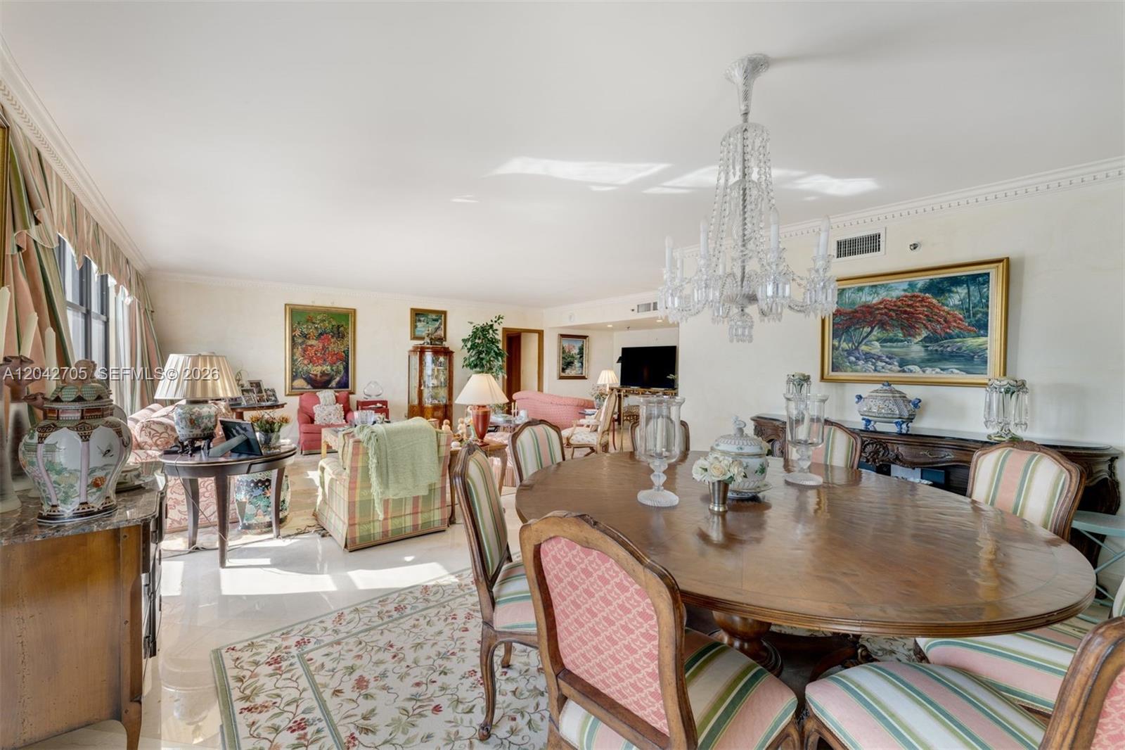 A dining and living area features a crystal chandelier, wooden table, and patterned chairs — 9 Island Ave # 1514, Miami Beach FL 33139, MIAMI BEACH, FL