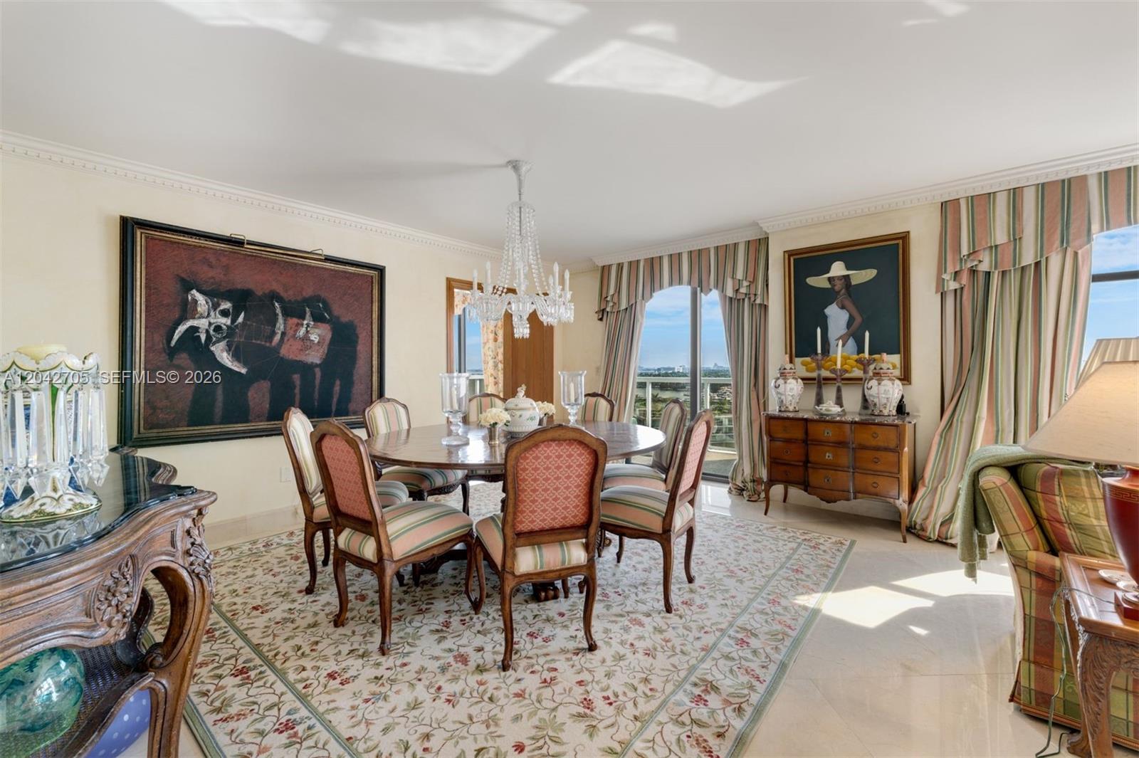 A formal dining room features a round wooden table, crystal chandelier, and patterned area rug — 9 Island Ave # 1514, Miami Beach FL 33139, MIAMI BEACH, FL