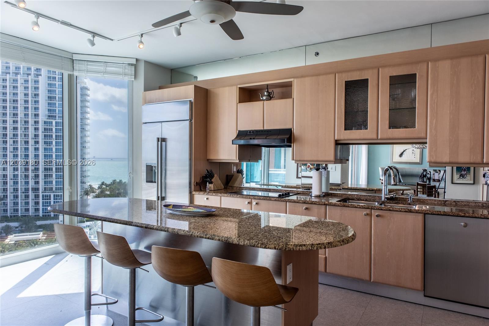 A kitchen with light wood cabinets, granite countertops, and a view of the ocean — 300 S Pointe Dr # 1502, Miami Beach FL 33139, MIAMI BEACH, FL