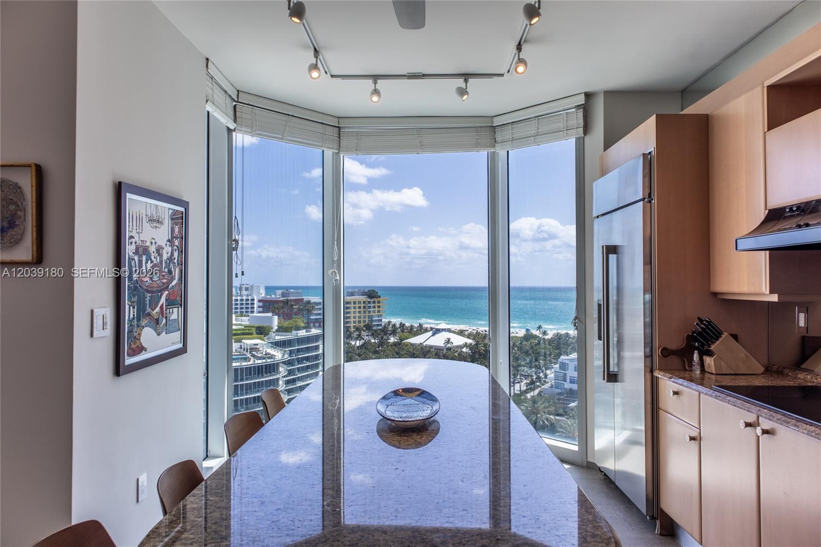 A kitchen with a granite island and floor-to-ceiling windows overlooking the ocean and city — 300 S Pointe Dr # 1502, Miami Beach FL 33139, MIAMI BEACH, FL