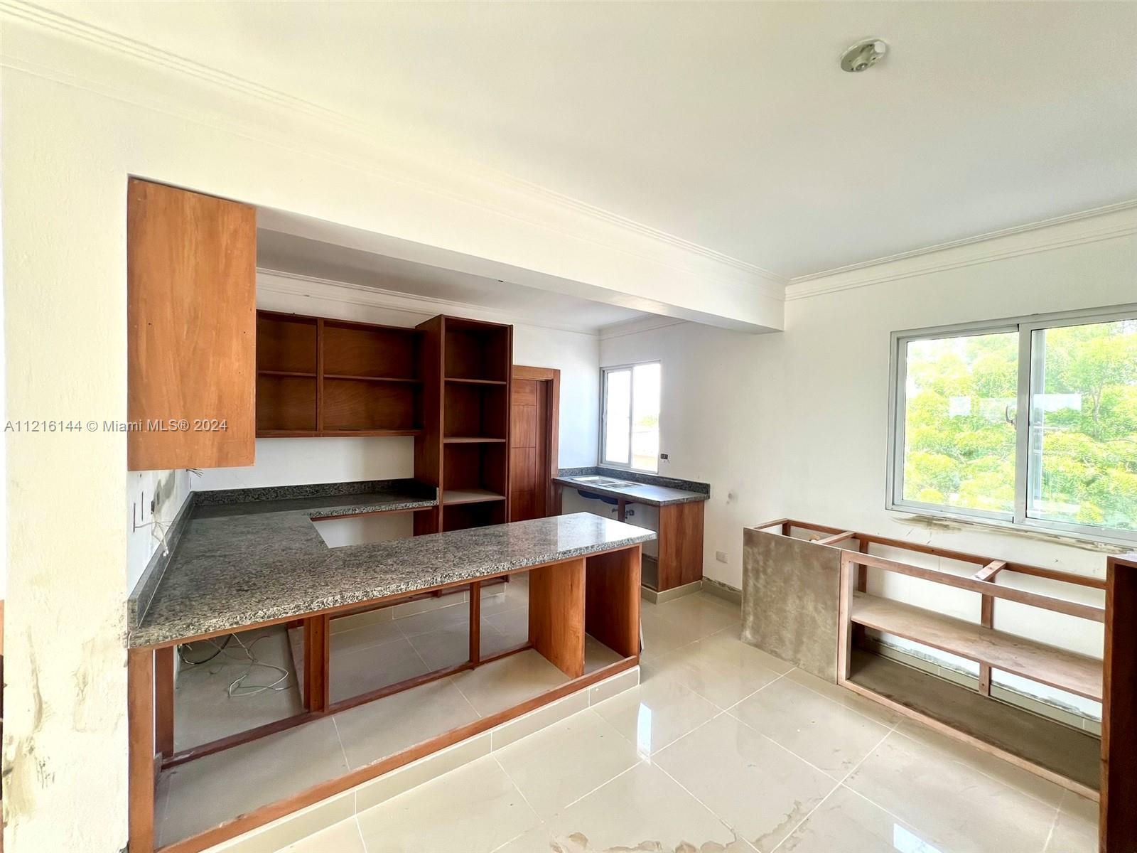 An unfinished kitchen features granite countertops, wooden cabinetry, and tiled flooring — Calle .. Esquina D-1 Villa Olimpica, Santiago # 2, DO, DO