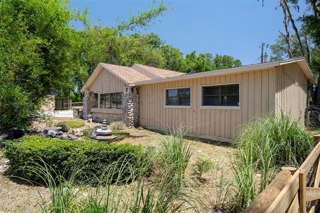 A single-story house with vertical wood siding and stone accents sits in a grassy yard — 3729 S LECANTO HIGHWAY, LECANTO, FL