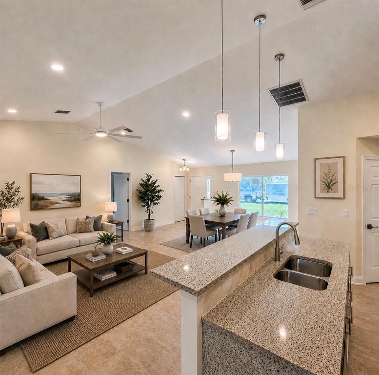 A kitchen island with granite countertops overlooks an open-concept living and dining area — 121 MARINER LANE, ROTONDA WEST, FL