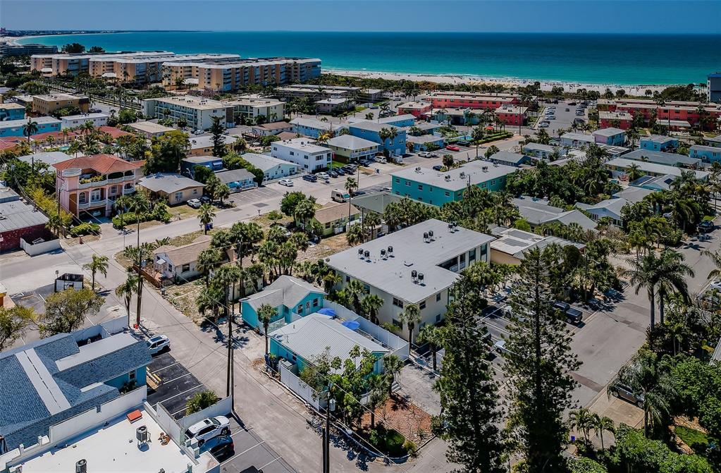 An aerial view shows a coastal neighborhood with multi-story buildings, houses, and palm trees — 504 70TH AVENUE, ST PETE BEACH, FL