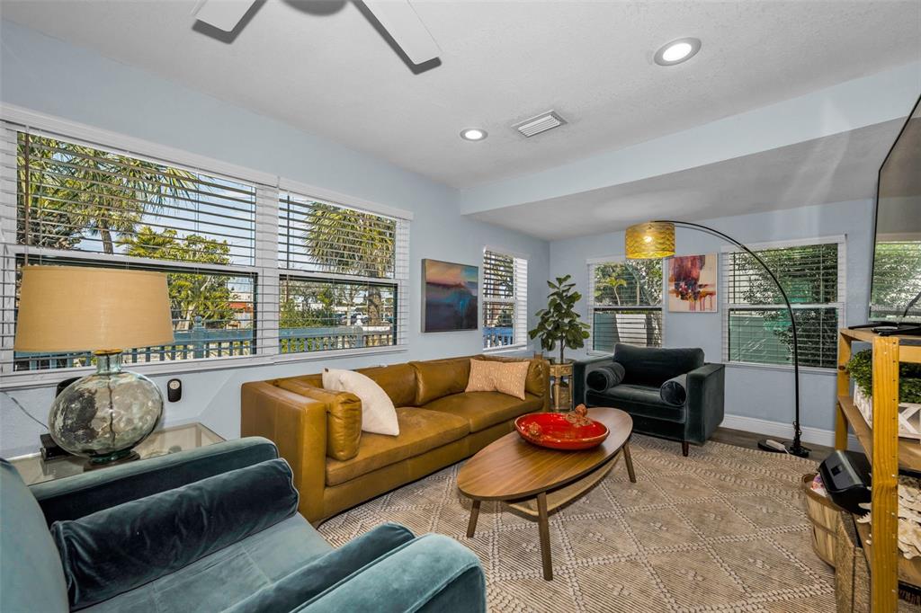 A living room features a tan leather sofa, two teal armchairs, and a wooden coffee table — 504 70TH AVENUE, ST PETE BEACH, FL