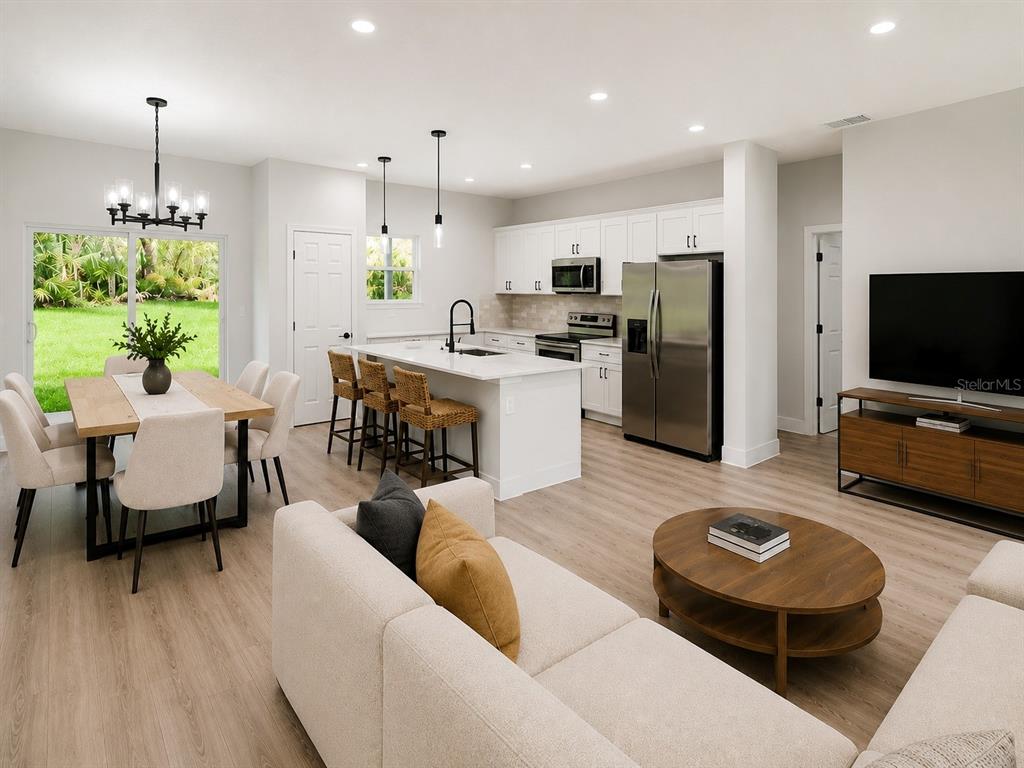 An open-concept kitchen, dining area, and living room feature white cabinetry and light wood floors — 8106 N GALENA AVENUE, CITRUS SPRINGS, FL