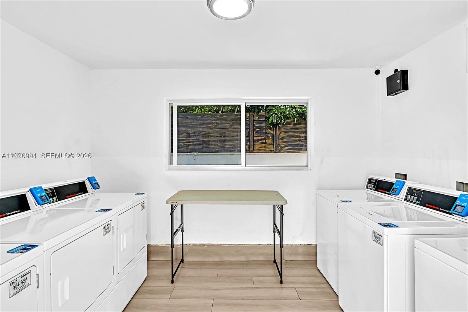 A laundry room features two white commercial washing machines, a folding table, and a window — 940 Michigan Ave # 10, Miami Beach FL 33139, MIAMI BEACH, FL